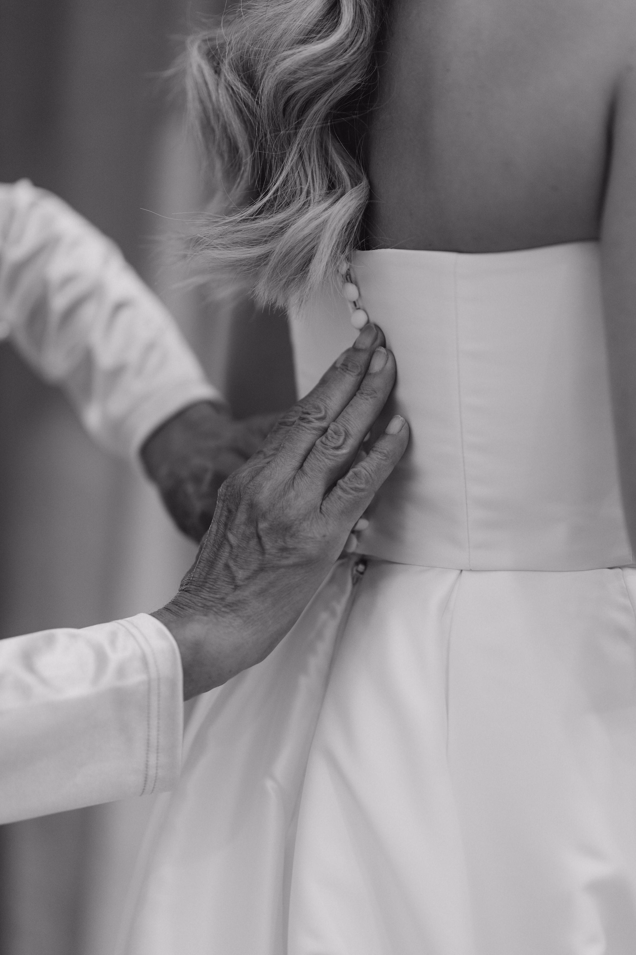 mother of the bride helping with dress during wedding morning preparation