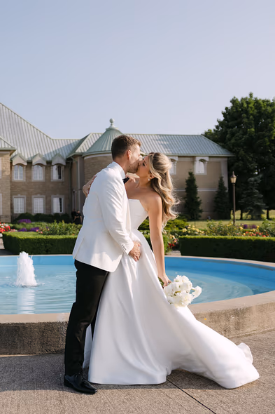 Bride and groom kissing by fountain at Château des Charmes wedding photographer session