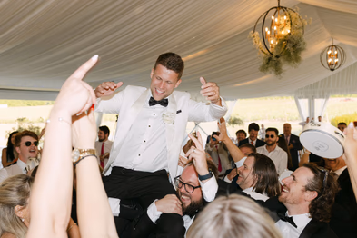 Groom lifted by guests during reception at Niagara-on-the-Lake winery wedding
