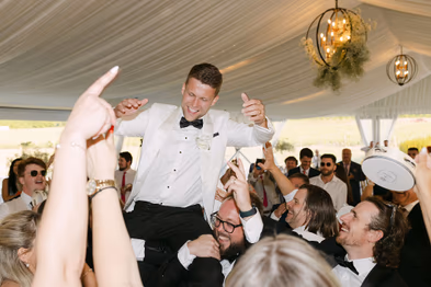 Groom lifted by guests during reception at Niagara-on-the-Lake winery wedding