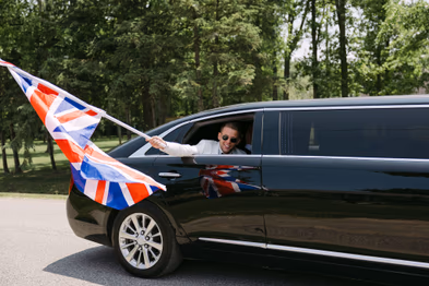 Wedding party celebrating with flags from limousine at Chateau des Charmes wedding