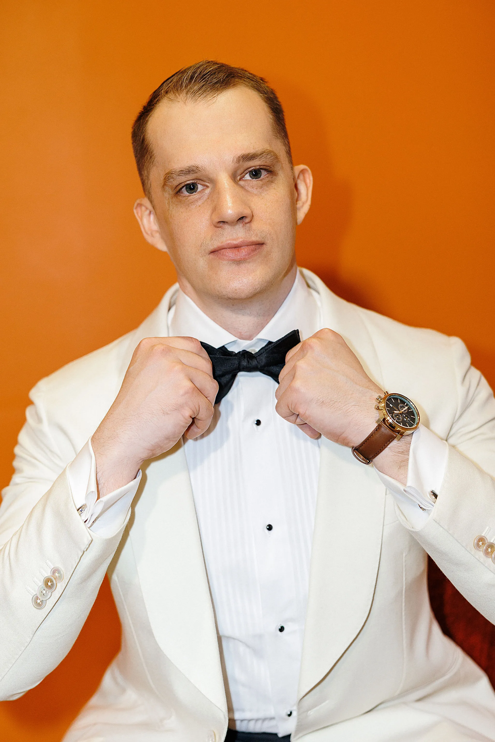 Groom fixing bow tie getting ready