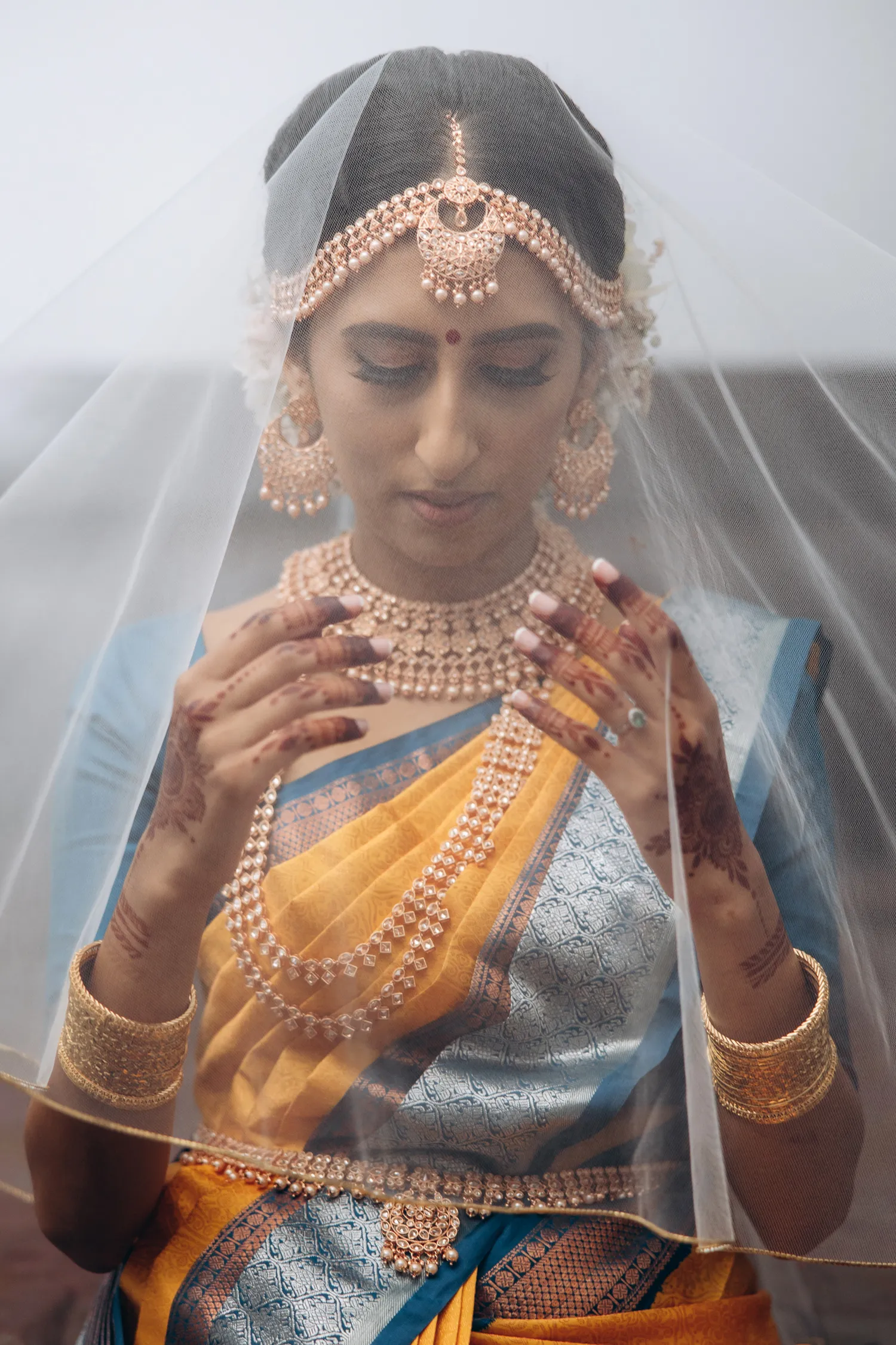 Bride wearing traditional blue saree under veil before Tamil wedding ceremony