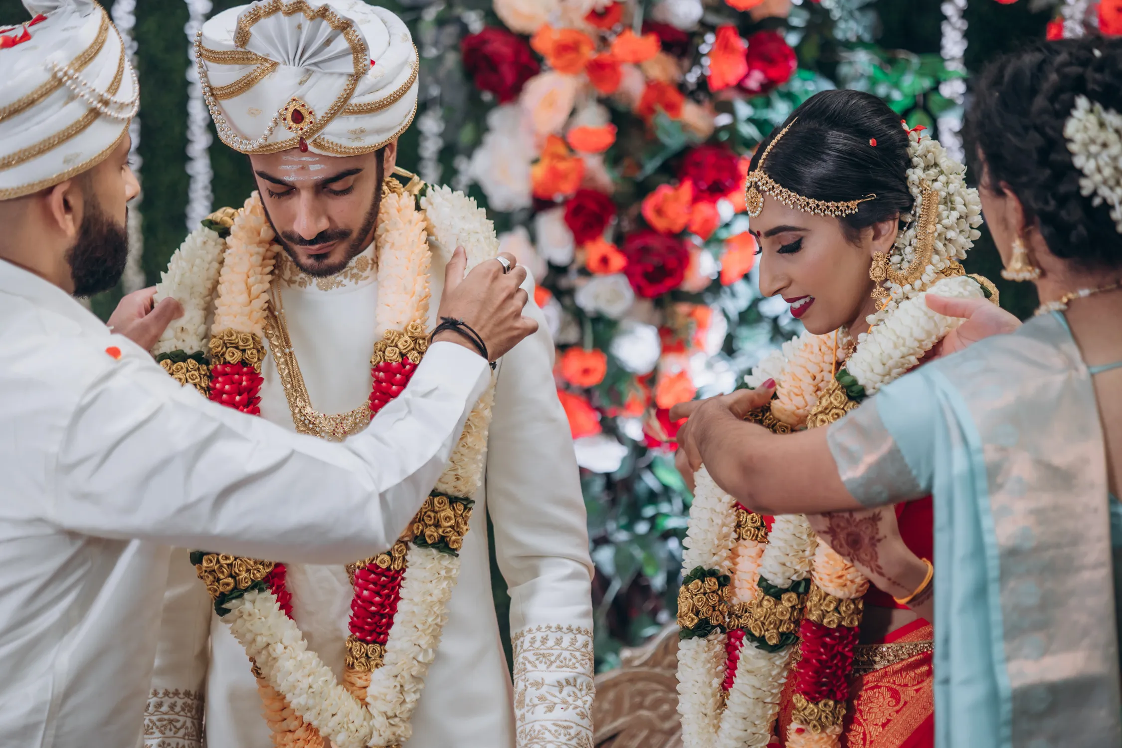 Bride and groom exchanging garlands at Tamil outdoor wedding in Madison Greenhouse