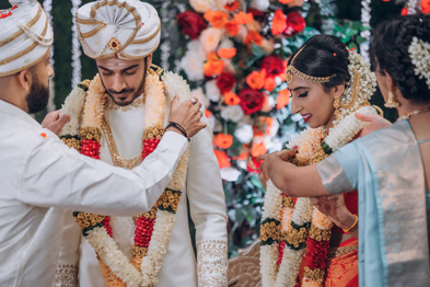 Bride and groom exchanging garlands at Tamil outdoor wedding in Madison Greenhouse